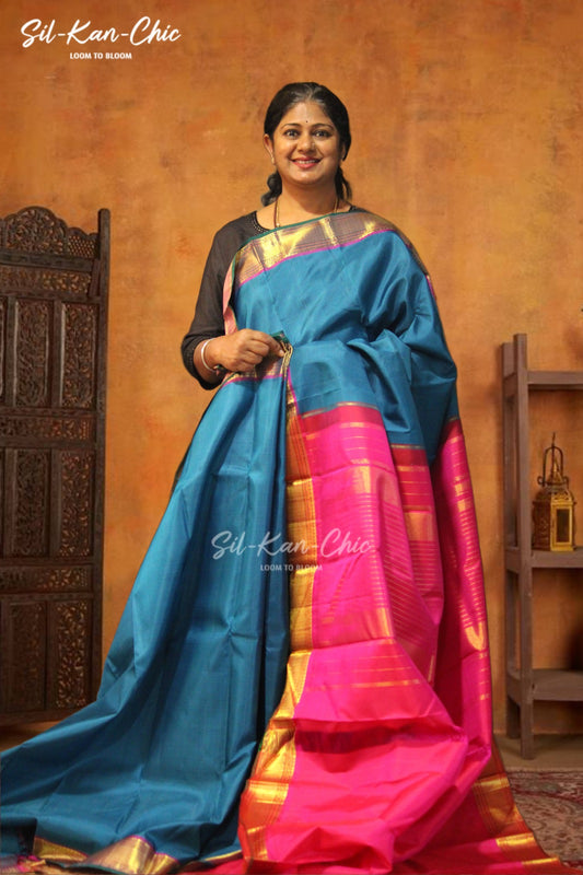 Blue with tiny checks in the body with gold zari bavanji border and a green selvage Rani pink contrast pallu and blouse Kanchipuram Silk Saree